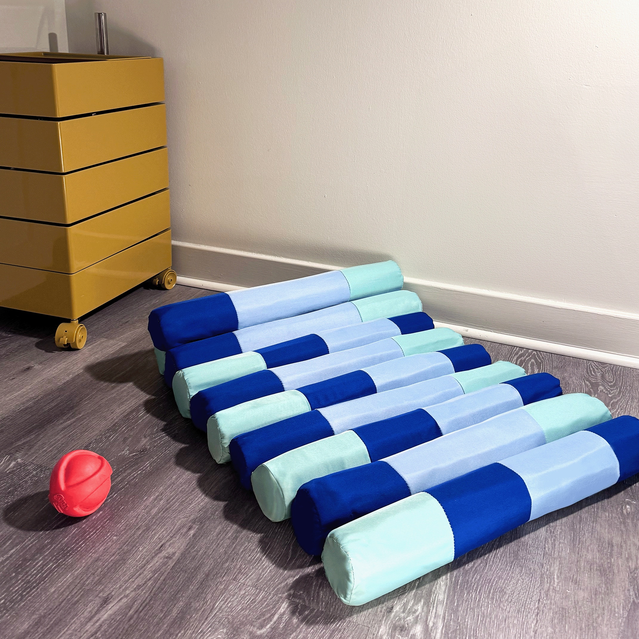The bed unrolled flat on the floor beside a yellow cabinet